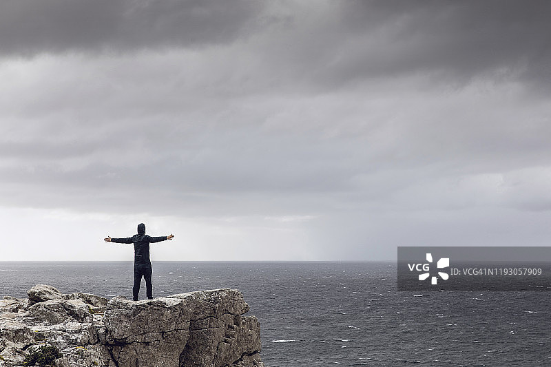 站在悬崖峭壁上眺望地平线的男子背影，南非西开普省开普角图片素材