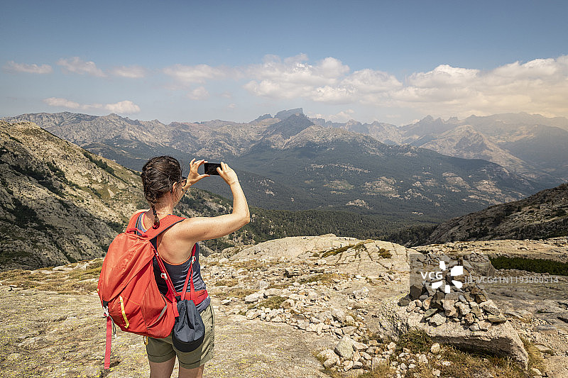 女徒步者在法国科西嘉岛徒步旅行时，拍摄沿途风景图片素材