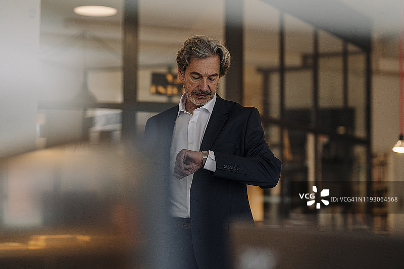 在办公室查看时间的高级商人图片素材