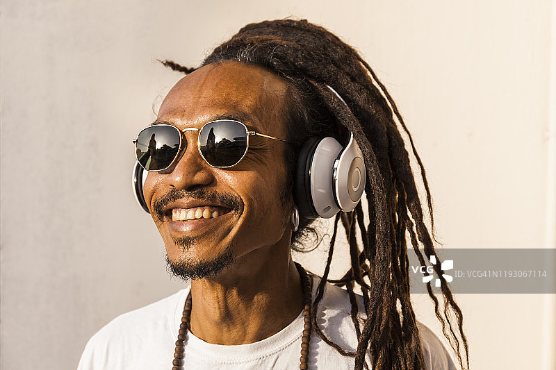 戴着脏辫和耳机，听着音乐，面带微笑，看向一边的中年男人肖像图片素材