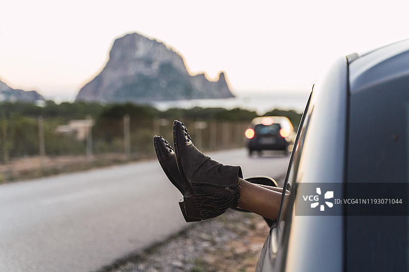 年轻女子在公路旅行中，将脚伸出窗外图片素材