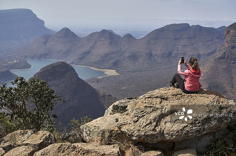 女人用手机拍摄美丽的风景背景，南非布莱德河峡谷图片素材