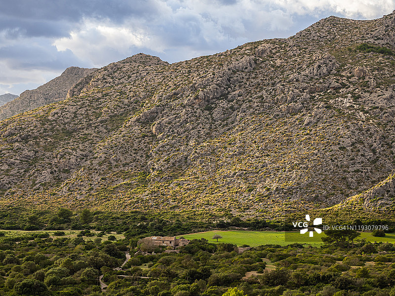 山脚下绿草甸山谷中的废弃房屋风景图片素材