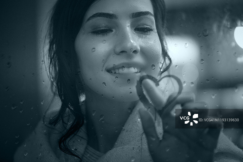 年轻女人在雾窗上画爱心图片素材
