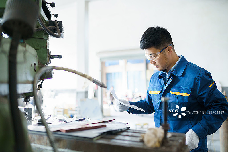 工业工程师在车床机旁研究蓝图图片素材