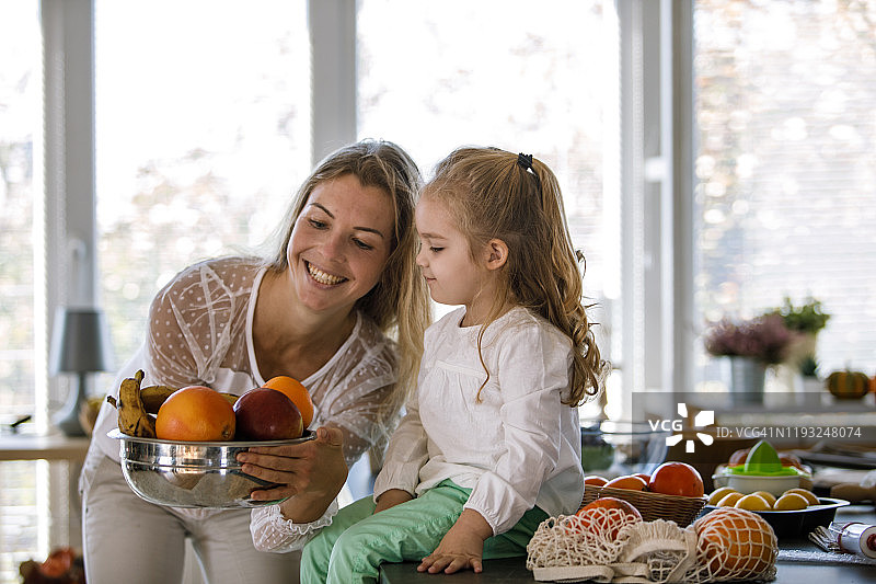 小女孩和妈妈一起看一碗新鲜水果图片素材