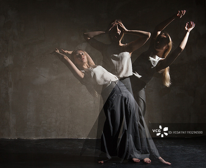 在黑暗房间里举手跳舞的艺术女人图片素材