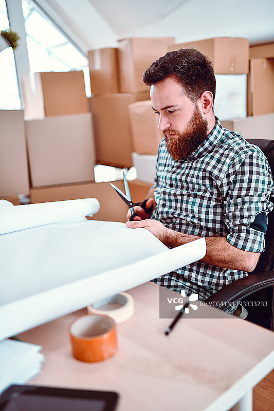 男人试图切割一大张纸做纸包装图片素材