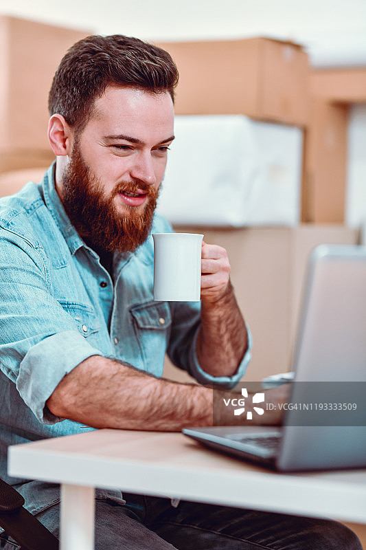 男人喝咖啡并用笔记本电脑建立视频会议图片素材