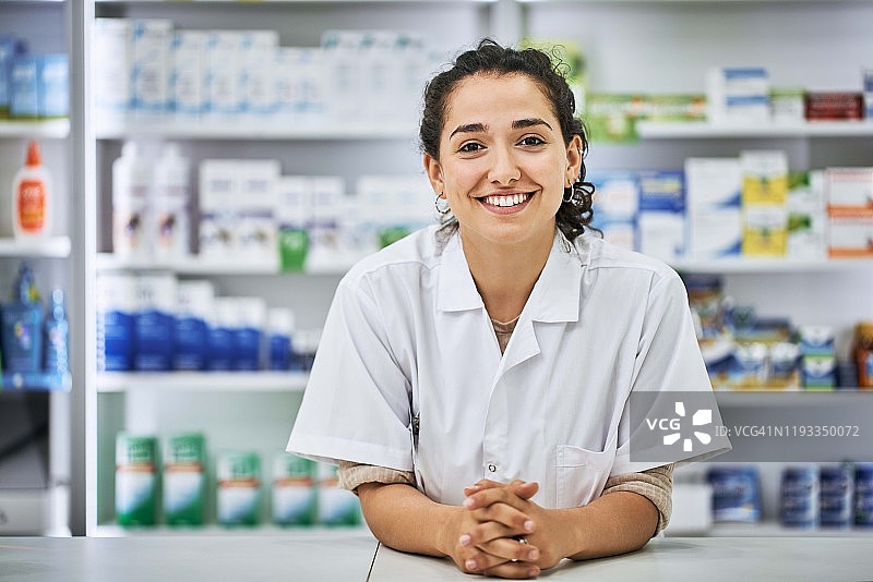 微笑的女药剂师靠在收银台旁图片素材