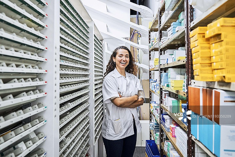 笑容满面的女化学师在商店里双臂交叉图片素材