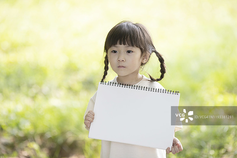 在公园里举着速写本的小女孩图片素材
