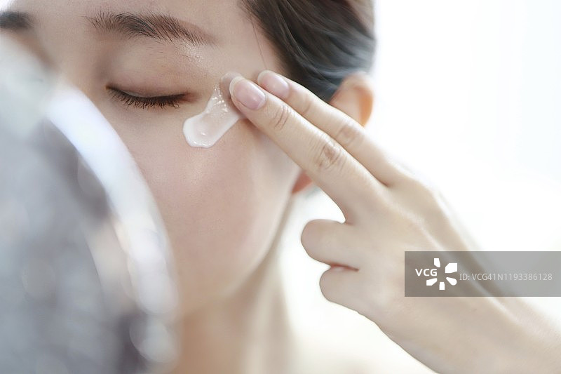 年轻女人涂抹眼霜图片素材