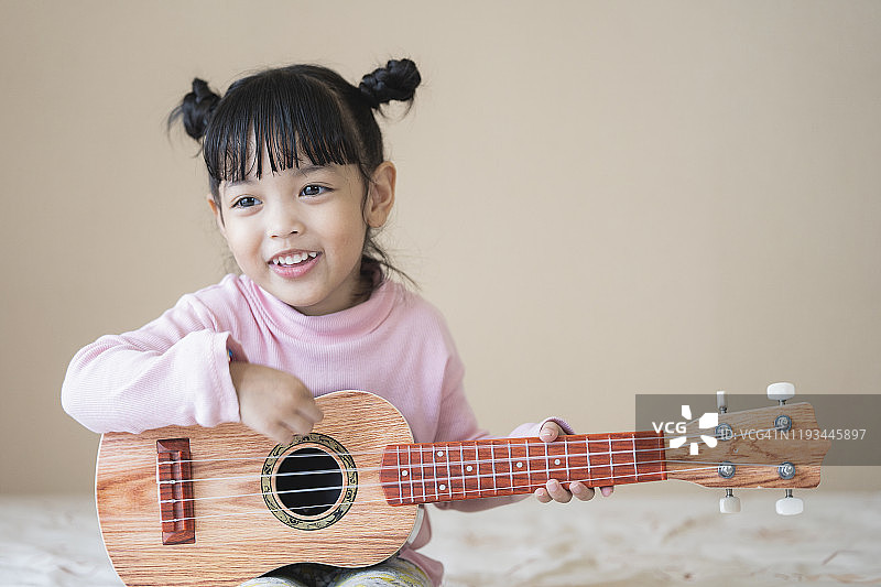 亚洲可爱女童快乐地弹吉他，音乐概念图片素材