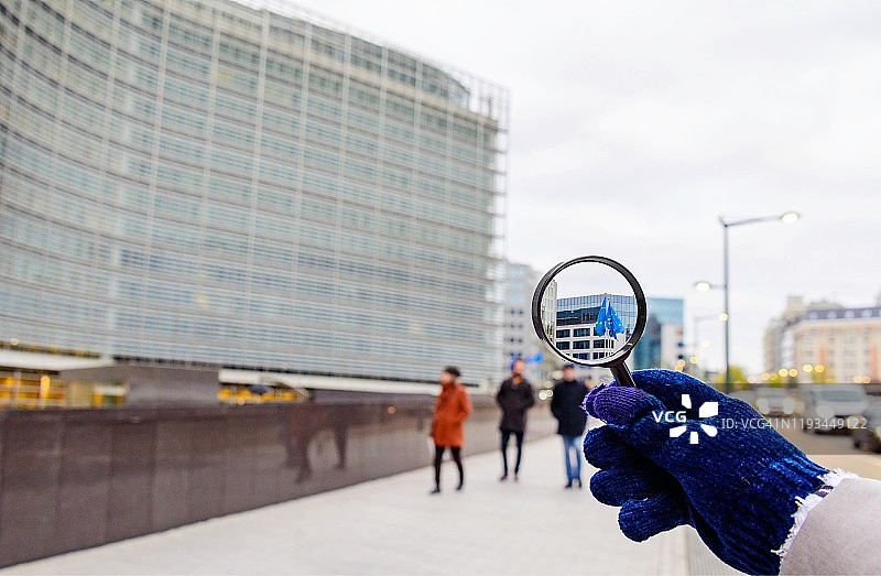 布鲁塞尔欧盟委员会前的欧盟旗帜与放大镜图片素材