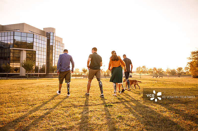 一群装有假肢的朋友在公园里行走的背影图片素材