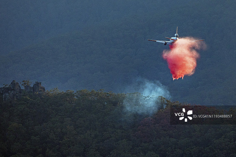 消防喷气式飞机在黄昏时分低空飞越澳大利亚蓝山山谷图片素材