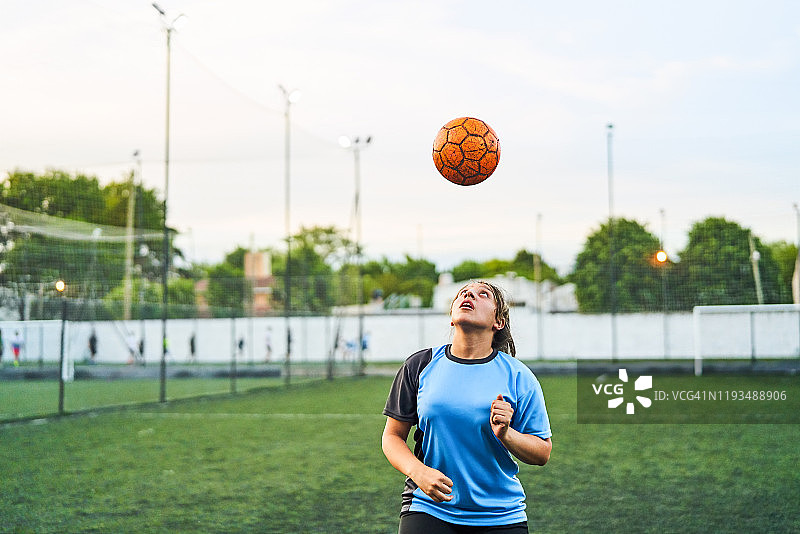 在运动场上头球的足球女孩图片素材