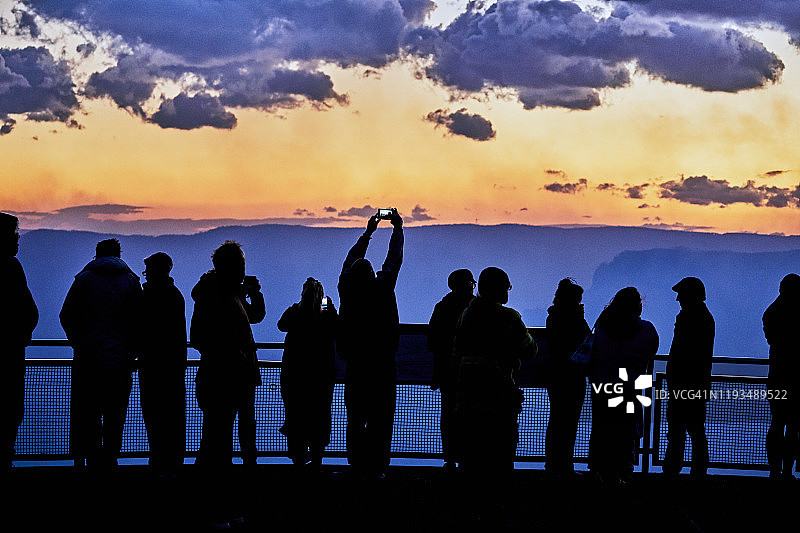 游客在观景台上观看黄昏时蓝山中烟雾弥漫的山谷的轮廓，澳大利亚图片素材