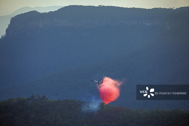 消防喷气式飞机在黄昏时分低空飞越澳大利亚蓝山山谷图片素材