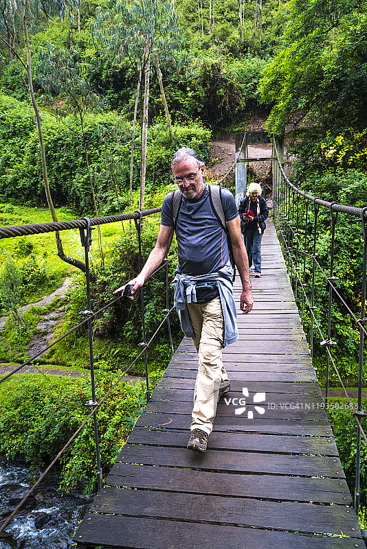 游客走过厄瓜多尔奥塔瓦洛附近，来自佩古切瀑布的河流上的悬索桥图片素材