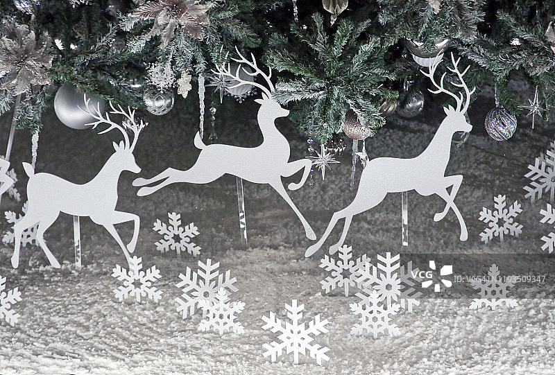 圣诞树下在假雪上奔跑的驯鹿图片素材