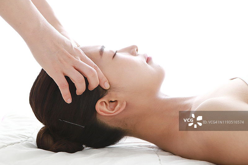 按摩治疗师为女士做面部按摩图片素材