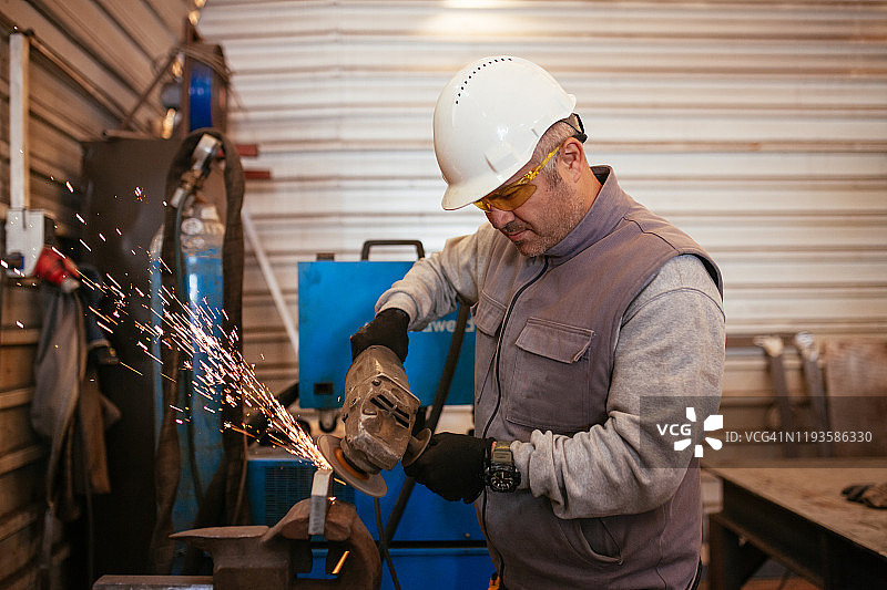 重工业工人用角磨机切割钢材图片素材
