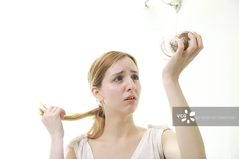 焦虑的女人拿着掉落的头发图片素材