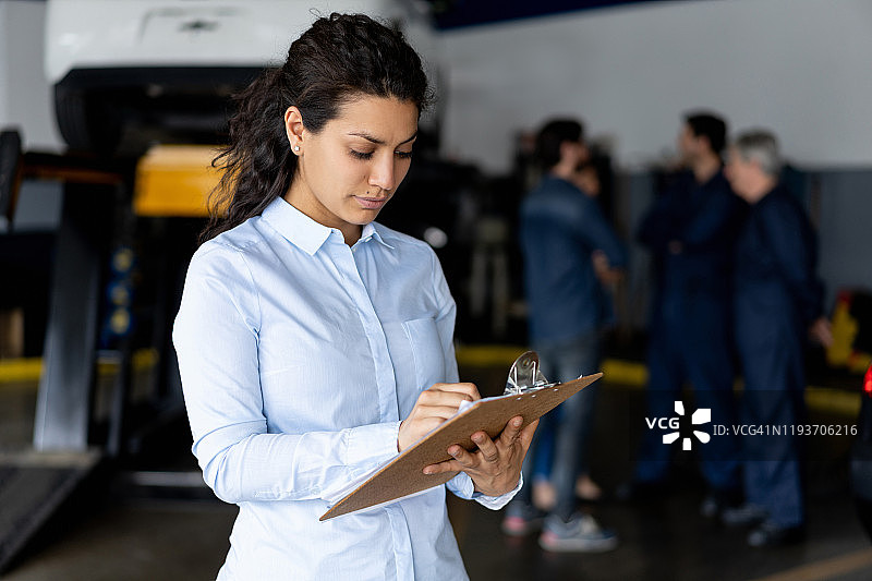 女助理核对服务清单，技工团队在背景图片素材