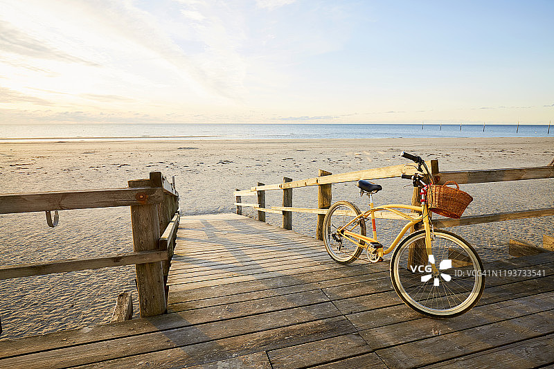 日出时分空旷海滩上的黄色沙滩自行车图片素材