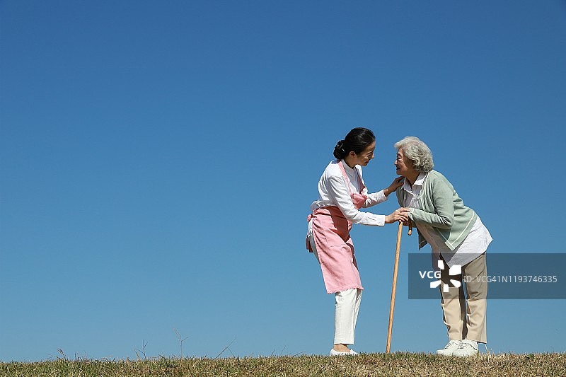 护士帮助拄着拐杖的老年妇女图片素材