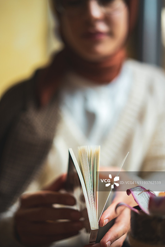 年轻女人坐在咖啡馆里看书图片素材