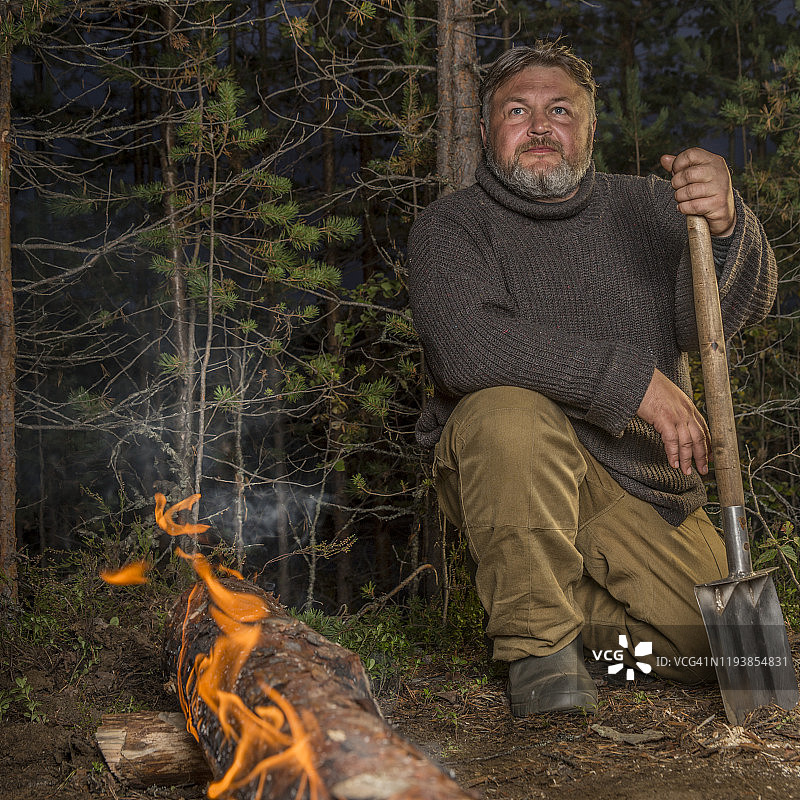 男子晚上坐在篝火旁图片素材