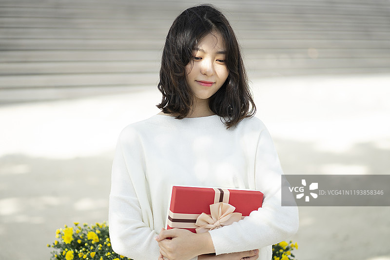 年轻女人在户外拿着礼品盒图片素材