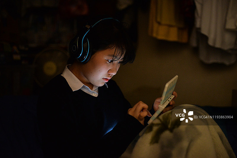 女孩在黑暗的房间里使用移动设备图片素材