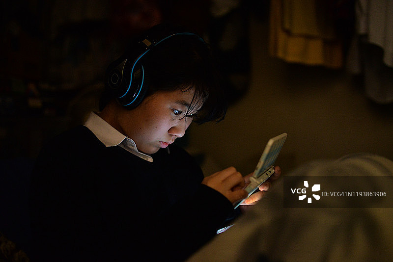 女孩在黑暗的房间里使用移动设备图片素材