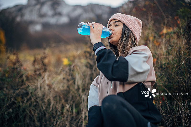 身穿运动服的年轻女子正在喝能量饮料图片素材
