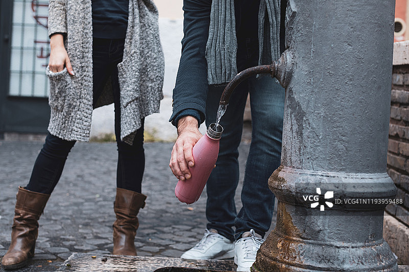 在罗马享受清凉：情侣在饮水机旁补充水分图片素材