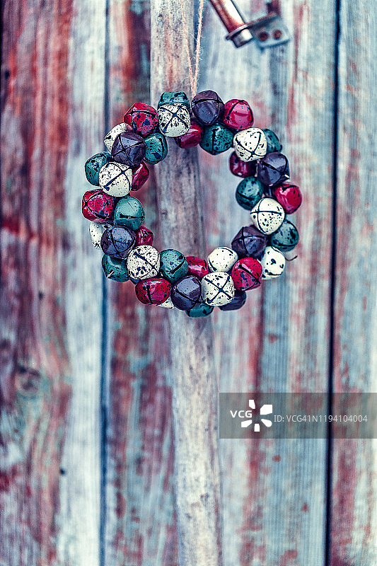 旧棕色木谷仓门金属把手上的圣诞铃铛花环图片素材