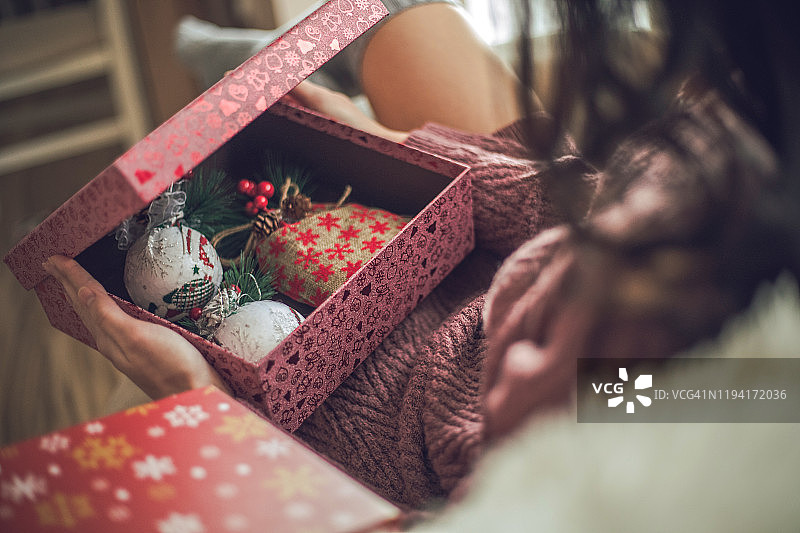 一位年轻漂亮的女孩在温馨的圣诞氛围中打开礼物图片素材