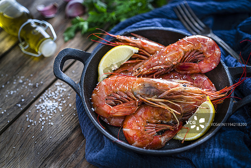 铸铁锅烤虾，置于木桌上图片素材