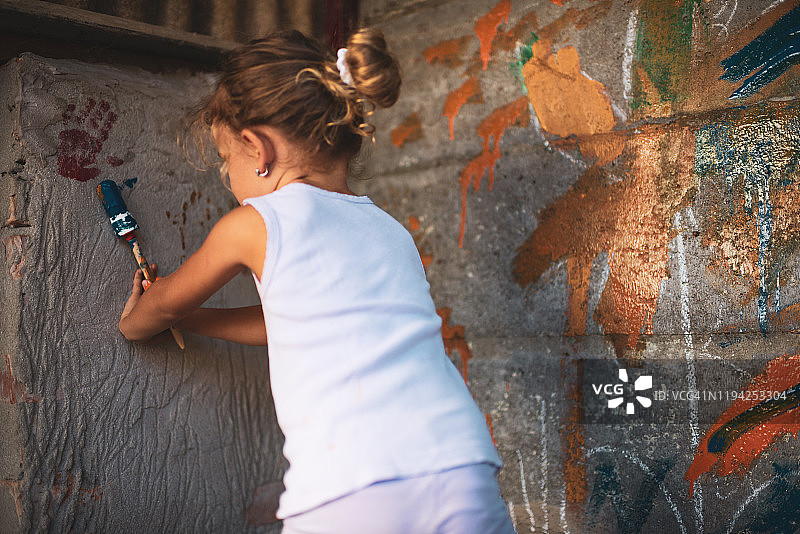 快乐的小女孩开心地在墙上绘画图片素材