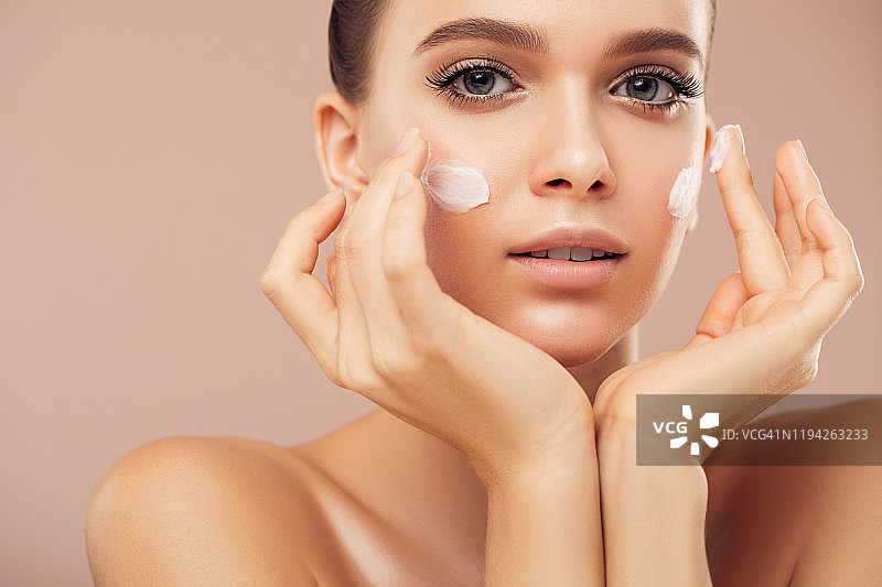美丽年轻的女人涂抹护肤霜图片素材