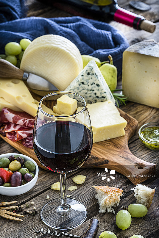 开胃菜：乡村木桌上的红酒杯、奶酪和腌制火腿图片素材