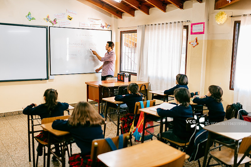 小学老师在教室里和学生一起工作图片素材
