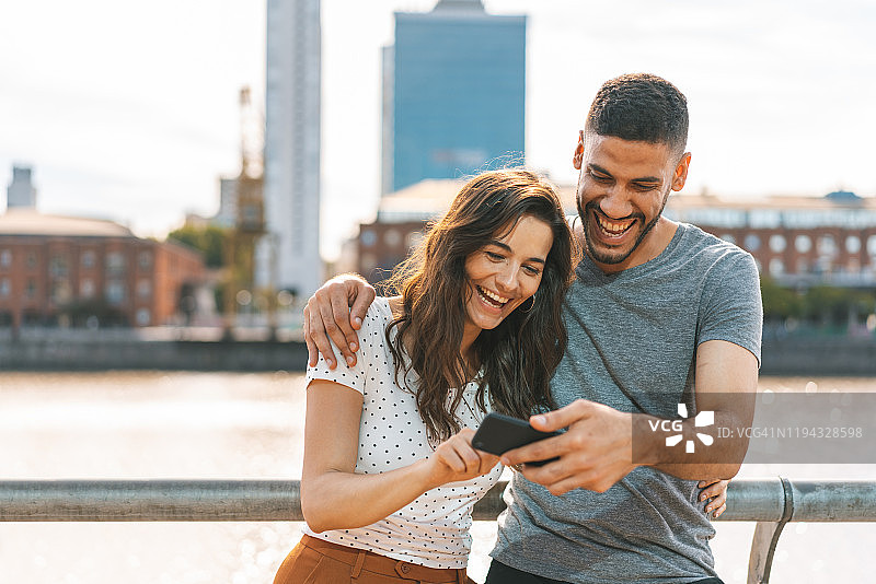 幸福情侣在智能手机上看视频，面带微笑图片素材