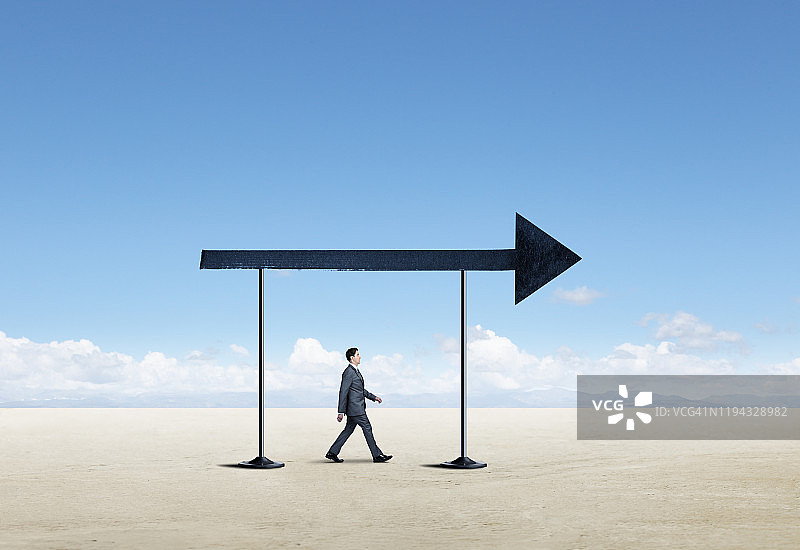 朝着箭头方向行走的商人图片素材