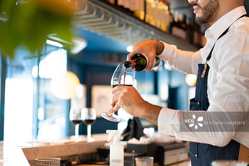 服务员往酒杯里倒葡萄酒图片素材