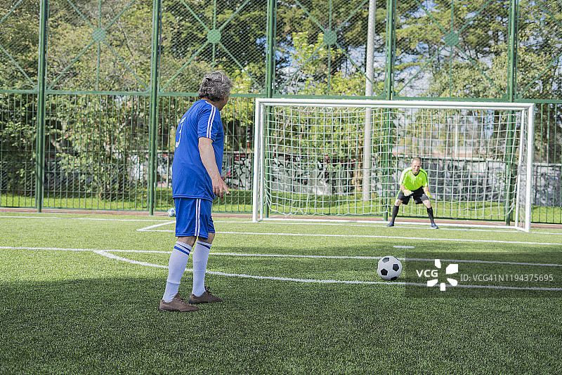 成年足球运动员点球射门，攻破守门员球门图片素材